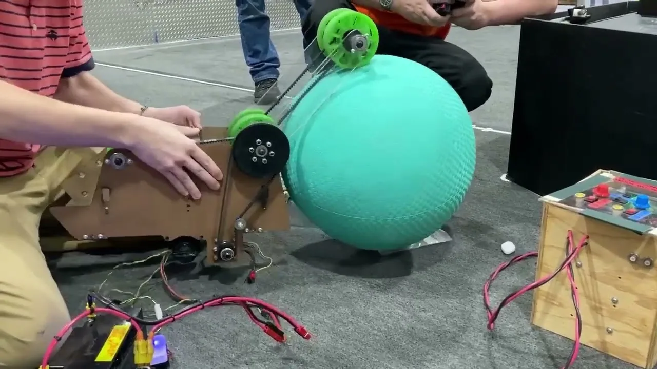 Algae intake prototype gripping a large teal ball on the practice floor