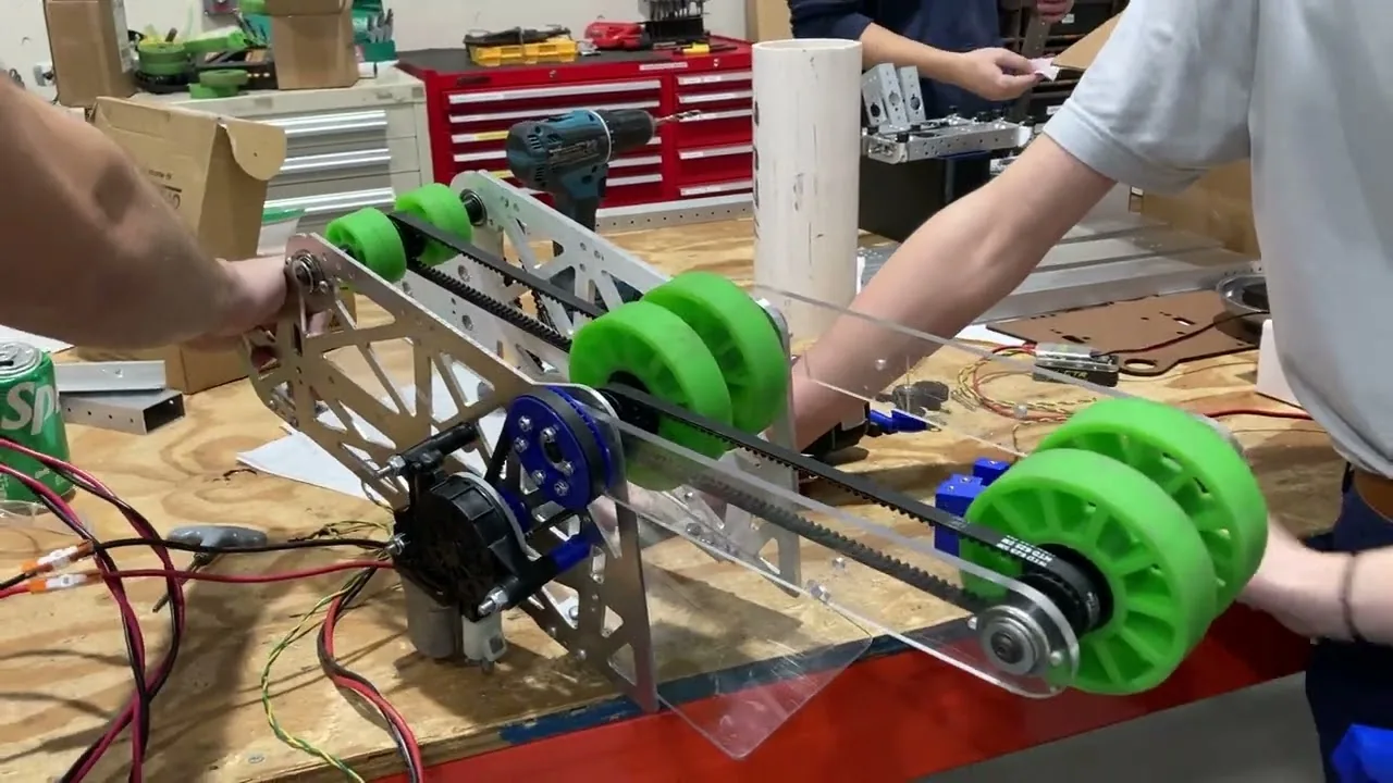 Coral chute prototype on a workbench with green compliant wheels, belts and a motor